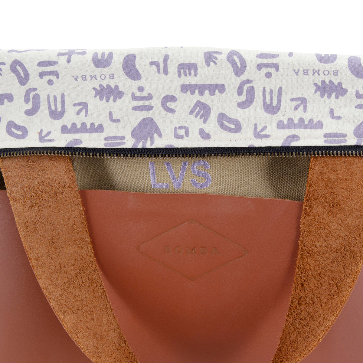 LVS initials embroidered in lilac above the embossed Bomba logo, with the lilac printed lining folded over the top.